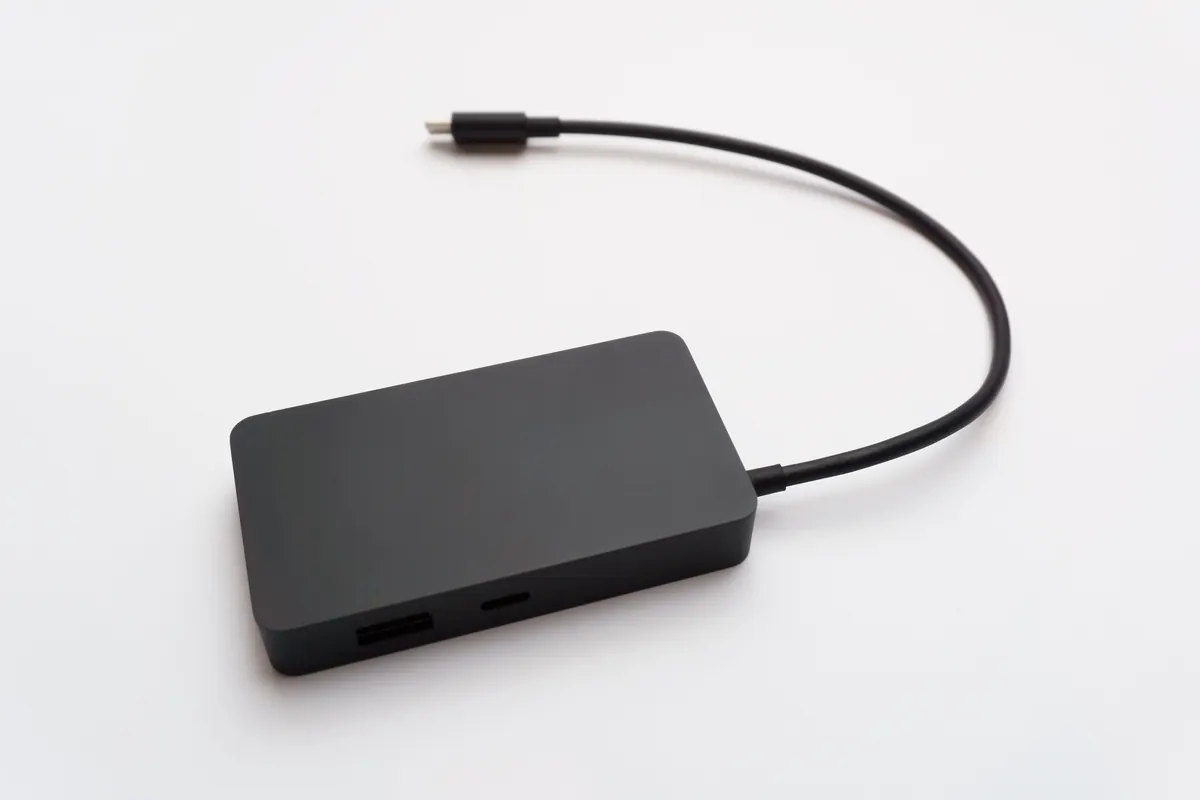 Gray multiport accessory with an attached cable on a pale surface.