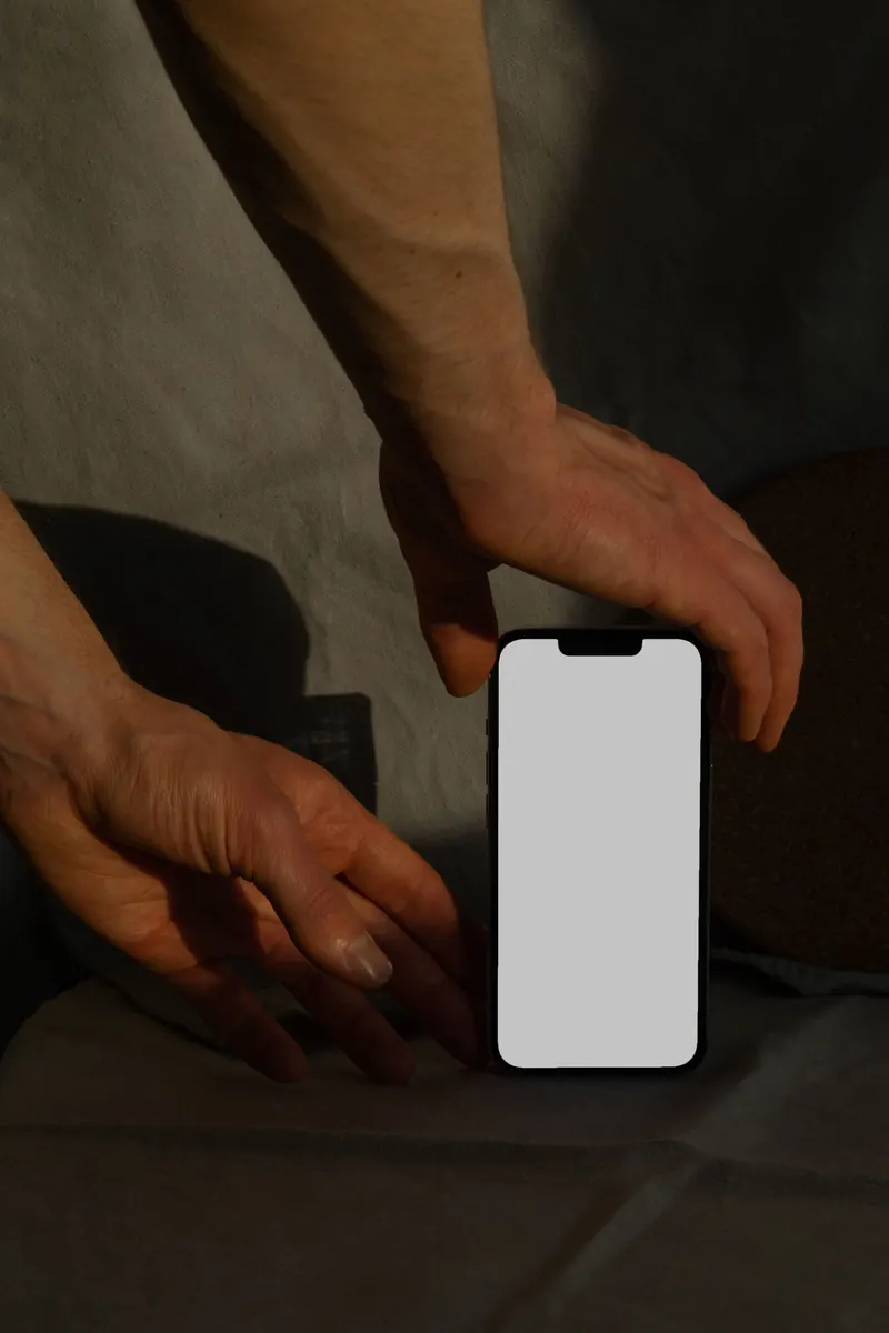 Hands placing a blank-screen phone on a table.