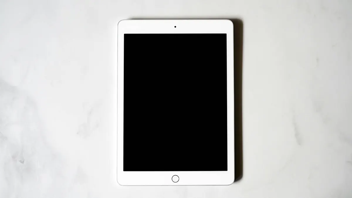 A white tablet with a dark screen, seen from above on a marble surface.